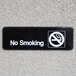 A black and white Vollrath Traex no smoking sign on a wall.