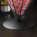 A black iron wire basket with red and white checkered paper inside.