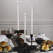 A table set with food, wine glasses, and white Hyoola taper candles.