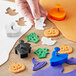 A person's hand holding a white plastic Ateco Halloween plunger cutter set with different shapes.