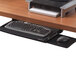 A black Fellowes keyboard drawer under a desk with a keyboard and mouse on it.
