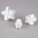 A group of white star shaped cookie cutters, including one with a plunger.