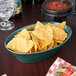 A large oval basket filled with chips on a table in a Mexican restaurant.