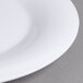 A close-up of a Carlisle white melamine plate with a wide white rim.