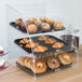 A Vollrath large clear acrylic bakery display case with trays of pastries and muffins inside.