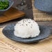 A rectangular blue stoneware plate with rice and black sesame seeds on it.