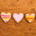 Four heart shaped cookies decorated with colorful frosting.