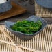 A blue stoneware bowl filled with green seaweed.