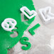 A green plastic Ateco alphabet and number cookie cutter set.