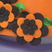 A cake decorated with orange and black flowers using Ateco 6-petal flower plunger cutters.
