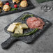 A Thunder Group Onyx Faux Marble melamine serving board with meat and cheese on it.