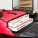 A red San Jamar insulated delivery bag with pizza boxes inside.