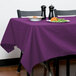 A table with a purple Intedge tablecloth and a plate of food.