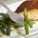 A 10 Strawberry Street Pearl stainless steel salad fork on a plate with meat and green beans.