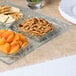 A Clipper Mill clear plastic 4-compartment tray of food on a table.
