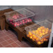 A Cambro brown slotted top bow tie dunnage rack holding plastic containers of apples and oranges.