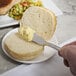 A person using a 10 Strawberry Street Pearl stainless steel butter knife to spread butter on a piece of bread.