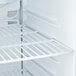 An Avantco white countertop refrigerator with shelves.