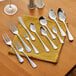 A group of Acopa Edgewood stainless steel dessert spoons on a yellow napkin.