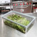 A clear plastic Cambro GripLid on a container of lettuce on a kitchen counter.