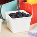 A white square GET Melamine crock filled with blackberries.