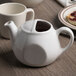A Tuxton porcelain white teapot on a white surface.