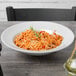 A Tuxton Pacifica bright white china pasta bowl filled with spaghetti on a table.