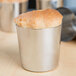A silver Matfer Bourgeat stainless steel cup with a piece of bread inside.