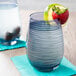 A Stolzle smoky blue stemless wine glass with a strawberry and lime slice on it.
