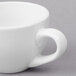 A close-up of a white porcelain espresso cup with a handle.