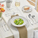 A table set with Acopa Monaca stainless steel dinner knives, forks, and plates.