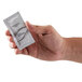 A hand holding a small white packet of Dial White Marble hand and body lotion.