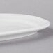 A close-up of a Libbey bright white porcelain racetrack plate with a curved edge.