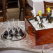 A Tablecraft translucent clear aluminum serpentine swirl table cover on a table with champagne bottles and glasses.