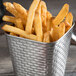A Tablecraft stainless steel square fry cup filled with french fries on a table.