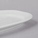 A close-up of a Libbey Bright White oval porcelain racetrack platter with a curved edge.