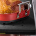 A Tablecraft black perforated carving station template holding cooked ham.