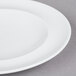 A close up of an Arcoroc white porcelain service plate with a white rim.