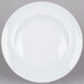 A close-up of an Arcoroc white porcelain service plate with a white rim.