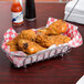 A Clipper Mill chrome oval wire basket filled with fried chicken on a table.