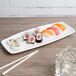 A Libbey bright white porcelain rectangular tray with sushi and chopsticks on it.