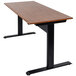 A Luxor black stand up desk with a wooden top and black base.