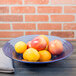 A table with a bowl of fruit including apples and oranges.