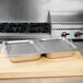 A Vollrath hinged flat steam table pan cover on a stainless steel pan on a counter.