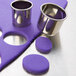 A purple piece of dough with metal oval and round cutters.