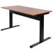 A wooden table with a black base and Luxor Pneumatic Adjustable Height Stand Up Desk on top.