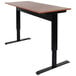 A Luxor 56" stand up desk with a black base and brown top.
