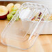 A clear Cambro deli crock lid on a table with fruit inside.