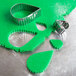 A metal Ateco fluted teardrop cookie cutter on green cookie dough.