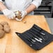 A person using Dexter-Russell garnishing tools to peel a potato on a cutting board.